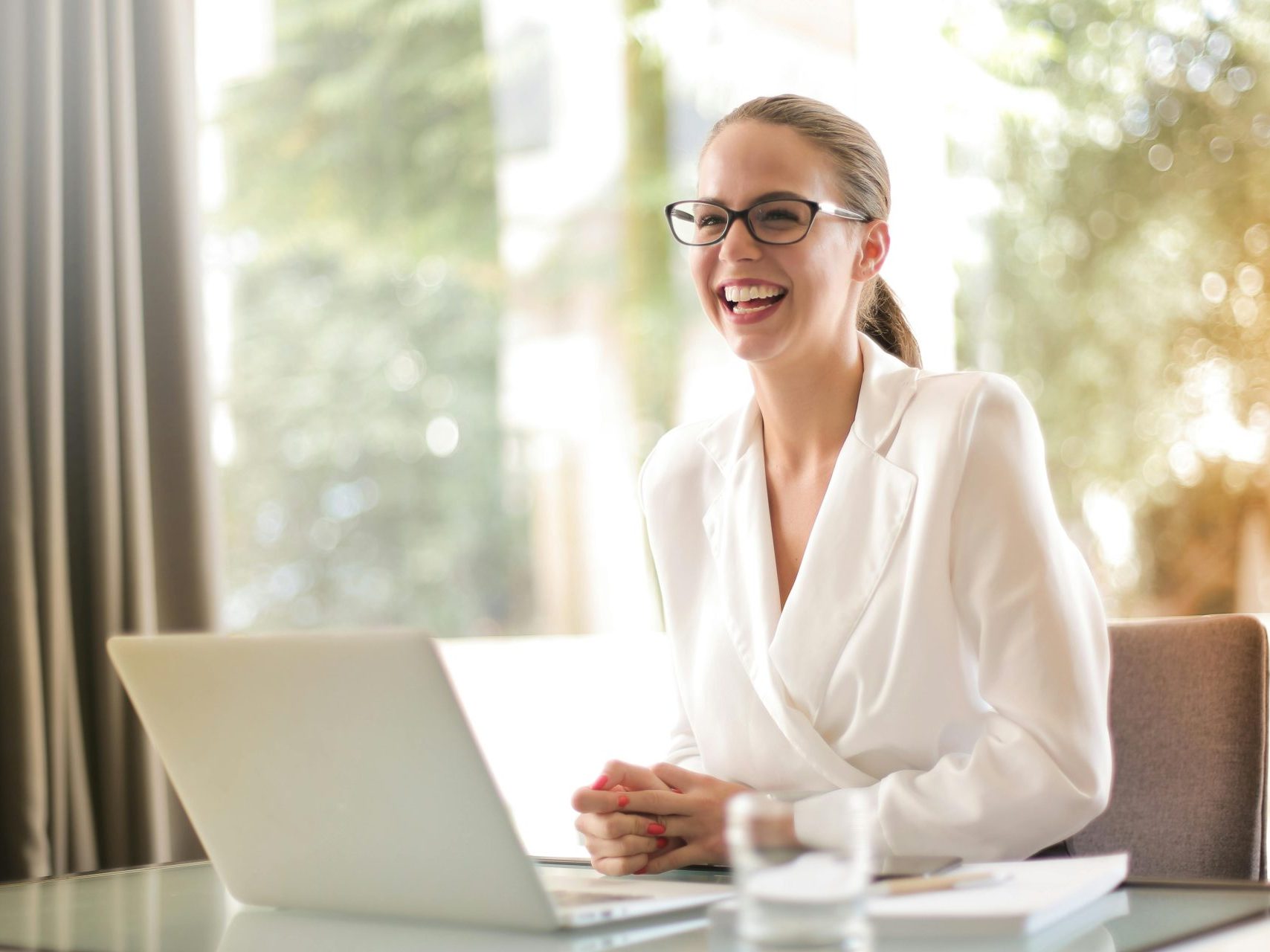 Laughing businesswoman working in office with laptop